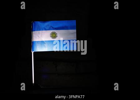 Bandiera argentina con bande blu chiaro e bianche e il Sole di Maggio è illuminato su tessuto nero che sventola dolcemente per esprimere lo spirito dell'unità della pampa Foto Stock