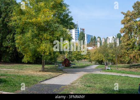 Sentieri lastricati e panchine tra alberi ed erba vicino agli edifici residenziali ai margini della valle di Prokop. Praga, Repubblica Ceca, 4 ottobre 2026. Foto Stock