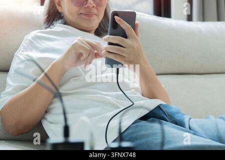 Un'autentica ripresa ravvicinata che si concentra sulle mani di una donna che tiene il suo smartphone. Sta nel processo o entrambi di collegare il cavo di ricarica al ph Foto Stock