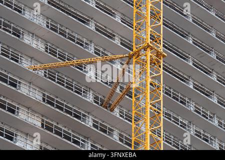 Una pesante staffa di ancoraggio collega la gru a torre alle lastre del piano di un moderno edificio in costruzione. Foto Stock