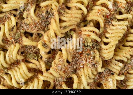 Macro di spaghetti Ramen istantanei secchi cosparsi di polvere di condimento ed erbe Foto Stock