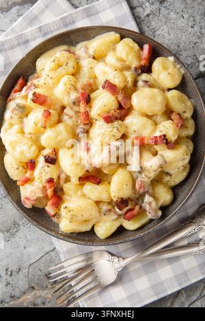 Gnocchi carbonara una rivisitazione confortante del classico piatto di pasta primo piano sul piatto sul tavolo. Vista verticale dall'alto Foto Stock