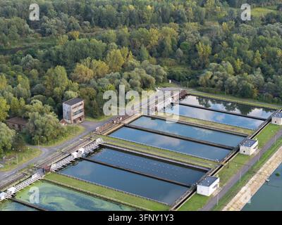 Vista aerea dei serbatoi di sedimentazione in un impianto di trattamento delle acque reflue circondato da una rigogliosa foresta verde a Cracovia, Voivodato della Piccola Polonia, Polonia. Foto Stock