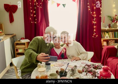 Coppia di anziani con nipote che scatta un selfie sullo smartphone Foto Stock
