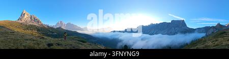 Una vista mozzafiato del Passo Giau rivela maestosi picchi e valli, avvolti nella nebbia mentre l'alba si apre sulle Dolomiti, Italia. Foto Stock
