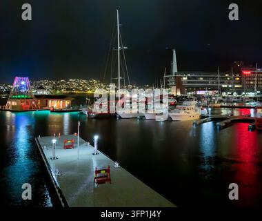 Porto e marina di Tromsø di notte con barche illuminate e riflessi della città, Norvegia Foto Stock
