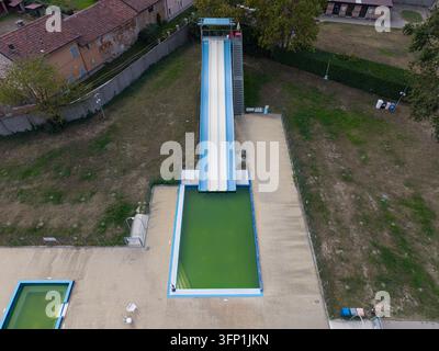 Vista aerea di uno scivolo d'acqua e di una piscina con acqua verde in un'area ricreativa a Chivasso, Piemonte, Italia. Foto Stock