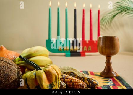 Kinara Kwanzaa con mishumaa saba, frutta fresca, verdure e mais su un tappeto intrecciato Foto Stock