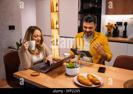 Coppia che lavora da casa in una cucina moderna Foto Stock