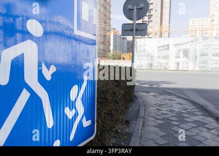Segnale di avvertimento per bambini su uno sfondo sfocato di una strada cittadina, cartello che indica bambini che giocano. Concetto di famiglia e bambini Foto Stock