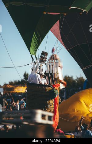 Bristol Balloon Fiesta, 7 agosto 2026, Regno Unito – Cesto di mongolfiera che si solleva nel cielo con pilota e passeggeri che salutano la folla del festival Foto Stock