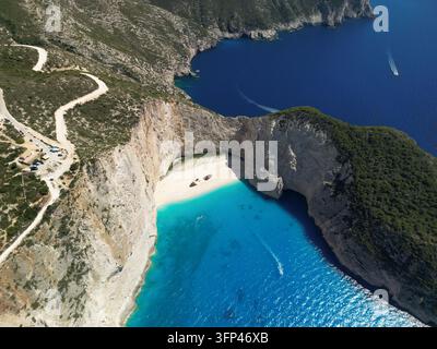 Vista aerea di una famosa baia isolata con acque marine turchesi vivaci incorniciata da imponenti scogliere rocciose bianche e colline verdi in Grecia. Foto Stock