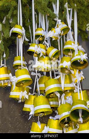 Campane gialle pendono dai rami di abete. Installazione natalizia. Foto Stock