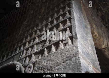 File di piccole figure di Buddha sedute scolpite in una parete di grotta, fotografate dal basso a Handan, Hebei, Cina. Foto Stock