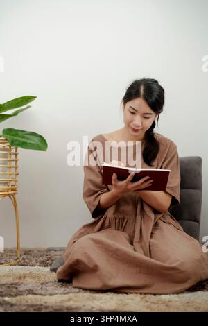 Mano di una donna che scrive una voce di diario in un diario a casa Foto Stock