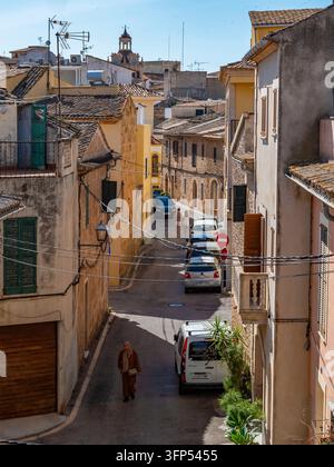 Incantevole strada acciottolata si snoda attraverso il centro storico della vecchia città di Alcudia, fiancheggiata da edifici in pietra consumati e tetti in terracotta in questo autentico Foto Stock
