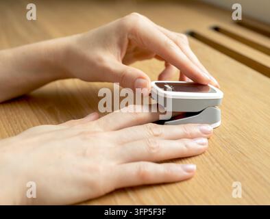 Premere il pulsante sull'ossimetro da polso mentre il dito è posizionato nella pinza per la lettura della saturazione di ossigeno. La mano attiva il sensore portatile per controllare la frequenza cardiaca e l'auto Foto Stock