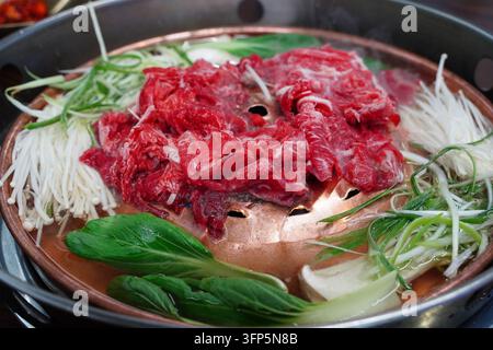 Manzo Bulgogi crudo marinato con funghi Enoki, cipolle verdi e bok choy su una tradizionale padella grill in rame Foto Stock