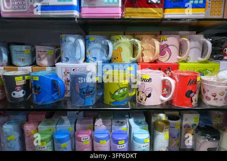 HONG KONG, CINA - 5 NOVEMBRE 2025: Scaffali di un negozio di giocattoli a Hong Kong. Tazze da bere con personaggi Disney su licenza: Paperino, Winnie the Foto Stock