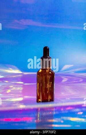 Siero oleoso in flacone di vetro con pipetta su sfondo rosa e viola, luce al neon con spazio di copia. Vista laterale cosmetica moderna e futuristica Foto Stock