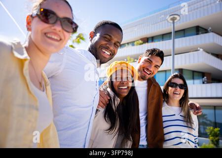 Amici diversi che sorridono, ridono, godono di una giornata vivace all'aperto Foto Stock