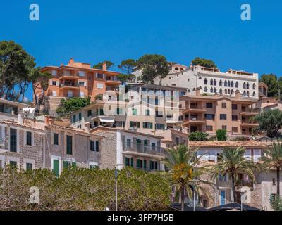 Port de Soller, città collinare di Maiorca con edifici immobiliari colorati, persiane verdi e palme sotto un cielo azzurro e limpido, Maiorca Foto Stock