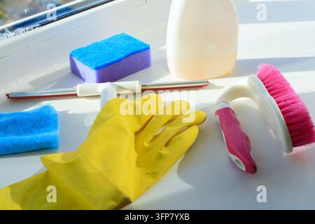 Set di attrezzature per la pulizia delle finestre con guanto per spolverare, spugna e flacone spray sul davanzale come concetto. Forniture per l'igiene domestica e strumenti detergenti per il vetro di casa Foto Stock