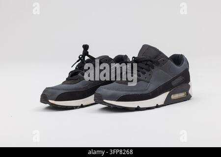 Foto prodotto in studio di un paio di scarpe da corsa nere con suole bianche, isolate su uno sfondo grigio chiaro. Modello di calzature sportive moderne Foto Stock