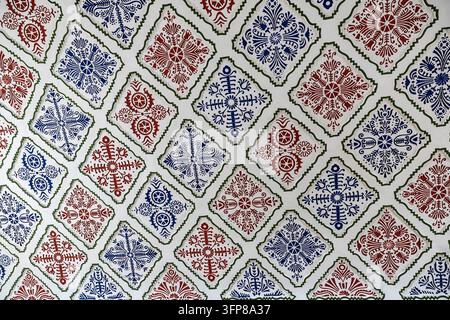 Motivi floreali rossi e blu intricati e ripetitivi su piastrelle bianche del soffitto, Municipio di Subotica, Subotica, Serbia Foto Stock