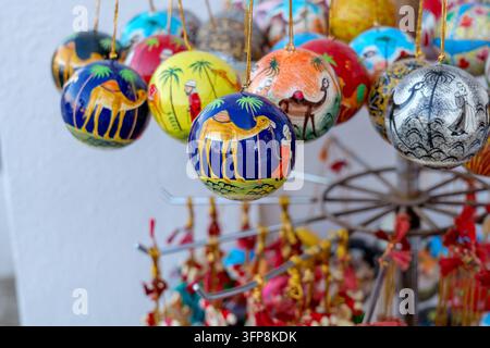Prima coloreggiata di ornamenti arabi sospesi fatti a mano con motivi tradizionali di cammello, luna e geometrici in un mercato dell'Oman, caratterizzati da colori vivaci Foto Stock