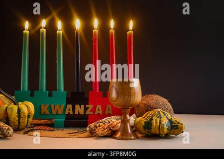 Kinara Kwanzaa con sette candele mishumaa saba accese e simboli del raccolto per la celebrazione delle feste Foto Stock