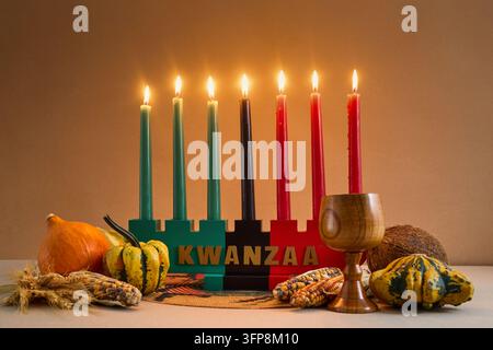 Kinara Kwanzaa con sette candele accese con raccolti e una coppa dell'unità Foto Stock