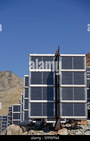 Dettaglio di pannelli solari in montagna montati verticalmente come quattro ali attorno a una colonna centrale a forma di albero, impianto fotovoltaico che evita l'accumulo di neve, futuro Foto Stock