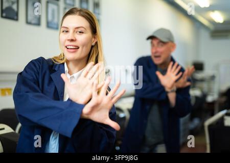 Donna positiva e collega maschio che ballano una danza divertente nella tipografia. Foto Stock