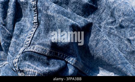 Tessuto di jeans blu con texture tessile piegata in primo piano Foto Stock