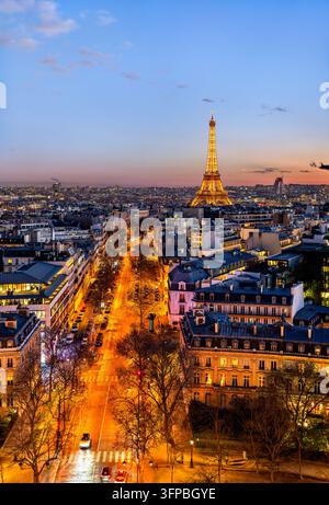 Parigi, Francia - 4 gennaio 2026: Vista elevata della Torre Eiffel illuminata e del traffico stradale parigino al crepuscolo dall’Arc de Triomphe. Foto Stock