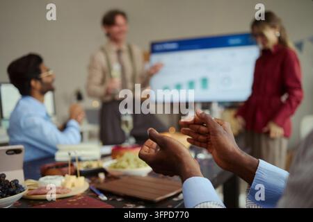 Mani di un uomo nero che applaude a una festa dell'ufficio Foto Stock