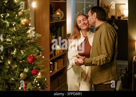 Coppia affettuosa che balla vicino all'albero di Natale a casa Foto Stock