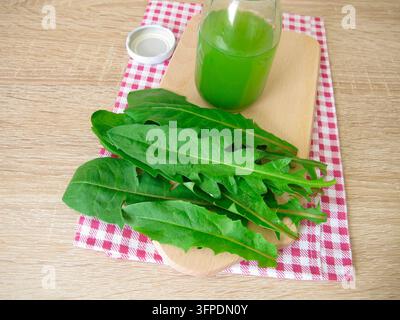 Una bottiglia di succo di tarassaco appena spremuto fatto da foglie di tarassaco fresche Foto Stock