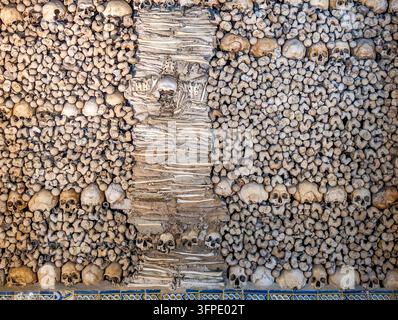 Teschi e ossa umani sul muro nella Cappella degli Ossi, Évora, Portogallo. Foto Stock