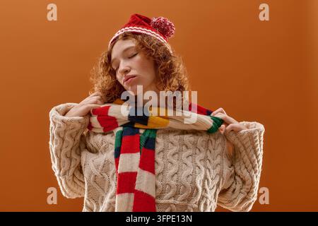 Una giovane donna con i capelli ricci gode del calore del suo abbigliamento invernale, posando con sicurezza. Foto Stock