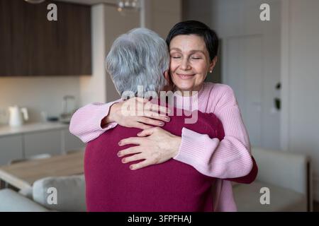 Moglie anziana sorridente e pacifica che abbraccia il marito, dimostrando connessione emotiva e armonia. Foto Stock
