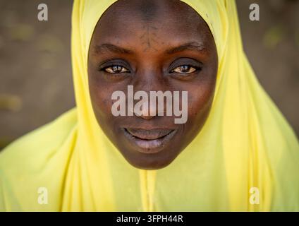 Ritratto ravvicinato di una donna sorridente con un hijab giallo e segni sul viso, Regione Bono Est, Kintampo, Ghana Foto Stock