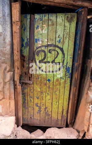 Porta di legno verde consumata con il numero 22 dipinto e A2 nell'area di Kibera, Contea di Nairobi, Nairobi, Kenya Foto Stock