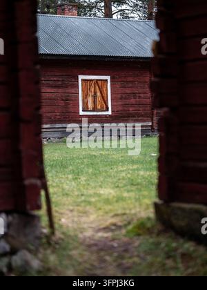 Edificio tradizionale in legno rosso con finestra con persiane e tetto in lamiera ondulata al Jokkmokk Hembygdsgård, un museo all'aperto del patrimonio nel nord della Svezia Foto Stock