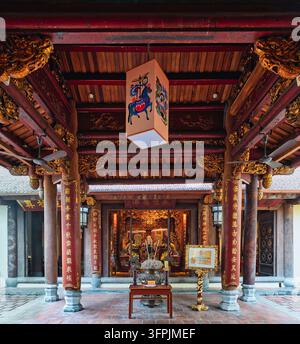 Colonne di legno ornate con calligrafia dorata e un altare tradizionale per l'incenso nel cortile del tempio storico di Bach Ma, un luogo religioso a Foto Stock