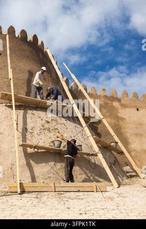 Lavoratori che applicano un nuovo strato di adobe alle pareti intorno all'Itchan Kala, la vecchia città di Khiva, in Uzbekistan Foto Stock