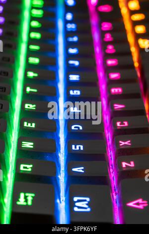 Vista su una tastiera da gioco che mostra una vivace retroilluminazione arcobaleno, collegando tecnologia e intrattenimento. Tasti illuminati in verde, blu e rosa Foto Stock