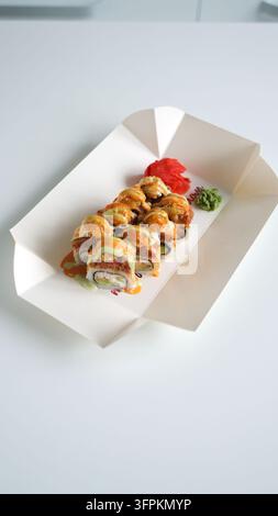 Rotoli di sushi speziati al forno con zenzero e wasabi in contenitore da asporto, un popolare piatto fusion giapponese Foto Stock