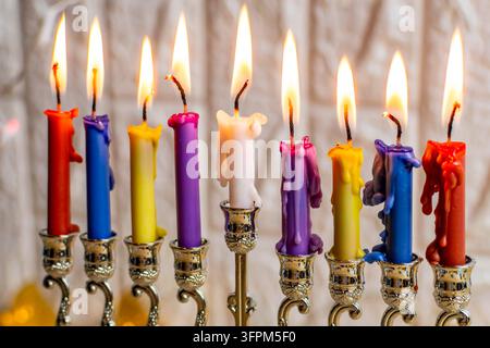 Candele colorate in una menorah che bruciano luminose durante la celebrazione ebraica di Chanukkah Foto Stock